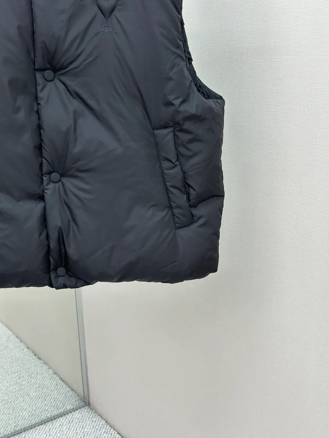 P810 AMIPARIS love padded embroidered down vest Fabric selection: Taffeta fabric woven from 100% polyester fiber. It adopts warp and weft plain weave and is woven very tightly, making the surface of the fabric extremely smooth and flat, with a "skinny" and stiffness that is not easy to collapse. When rubbed or moved around, it will make a unique, crisp "rustling" sound. At the same time, it has a delicate plain texture and a soft, elegant silky luster. This kind of luster is not as dazzling as satin, but more restrained and advanced.  Lining selection: Use 100% nylon to create the lining. The high-density and tight weaving process prevents tiny lint from getting out of the gaps in the fabric. The smooth surface improves the putting on and taking off experience, and the excellent wear and tear resistance ensures damage caused by frequent use, while the light and soft texture does not affect the overall weight.  Technology: The fabric and padding material are tightly fixed on the frame of the embroidery machine. The embroidery machine uses sparse stitches along the padding layer to outline the filling area of the pattern, and then runs the overlay layer's padding, using dense stitches to perfectly cover the foam padding layer, thus forming a slightly raised love embroidery, which feels soft and full, enhancing recognition while maintaining a low profile. High-quality filling: It uses 90 white duck down with a weight of 160g to ensure excellent thermal insulation performance. After strict screening and processing, the velvet is not easy to get drilled, ensuring durability.  Accessories: One-to-one customized three-standard, one-to-one customized hem elastic buckle, one-to-one customized snap button SIZE: XS S M L